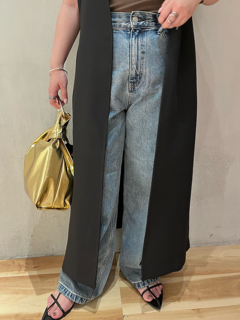 ブラック系のベスト、ブラウン系のタンクトップ、ブルー系のデニムパンツを着用したレディースの夏コーディネートの8枚目の写真