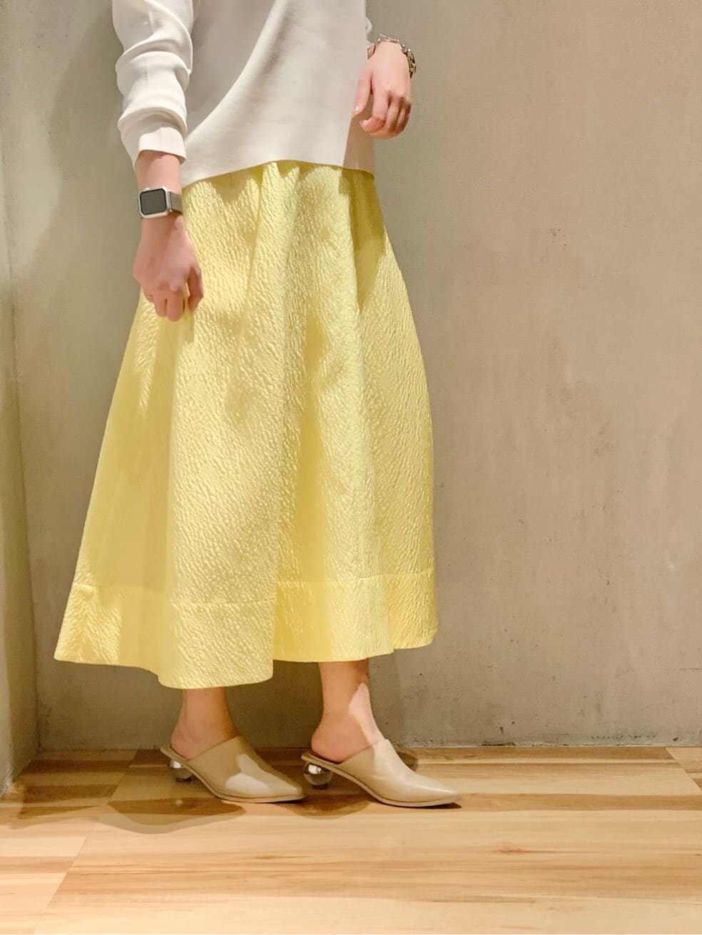 イエロー系のスカート、ホワイト系のニット/セーターを着用したレディースの冬コーディネートの5枚目の写真