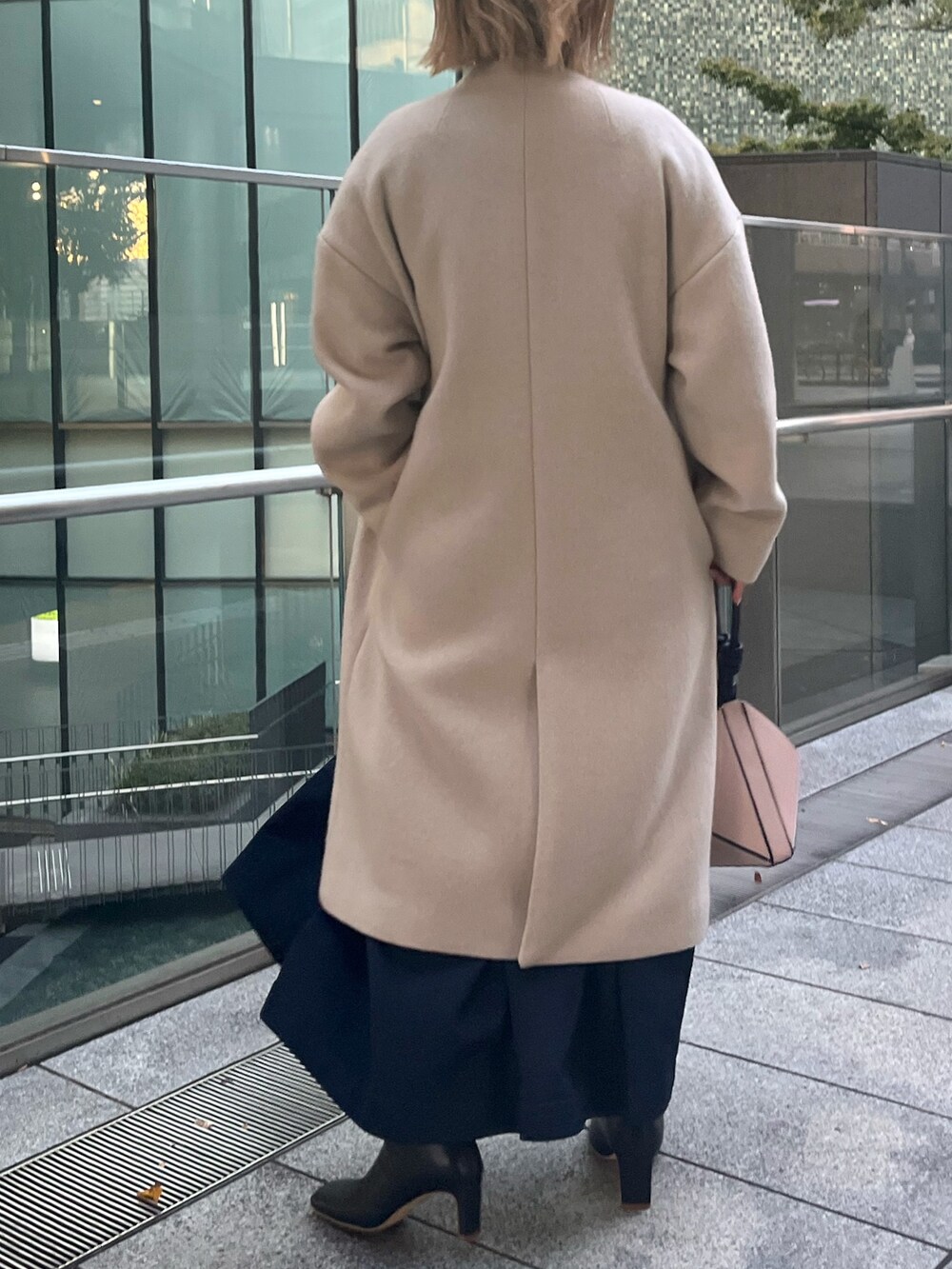 ブラック系のブーツ、ブルー系のワンピース、ベージュ系のハンドバッグを着用したレディースの秋コーディネートの3枚目の写真