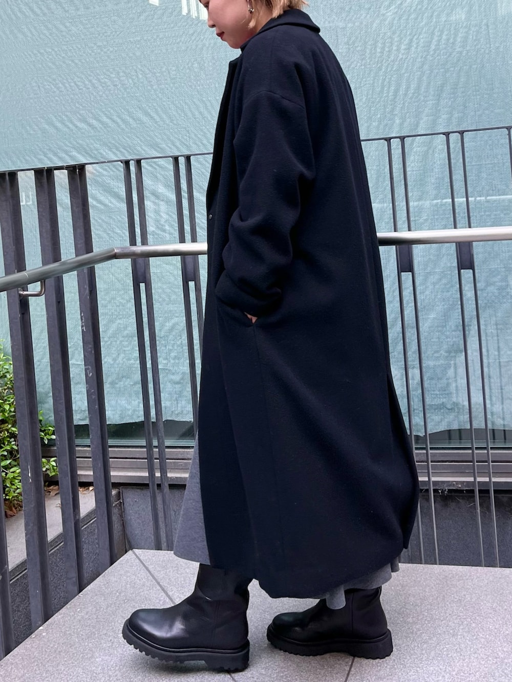 ピンク系のニット/セーター、ブラック系のチェスターコート、グレー系のスカートを着用したレディースの冬コーディネートの5枚目の写真