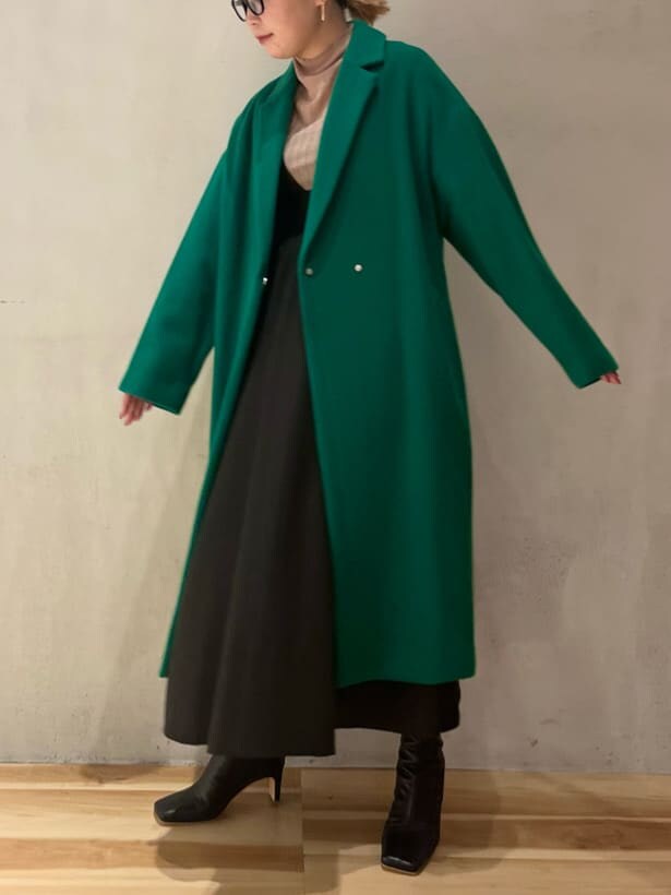 ブラック系のジャンパースカート、ブラウン系のニット/セーター、グリーン系のチェスターコートを着用したレディースの秋コーディネートの4枚目の写真