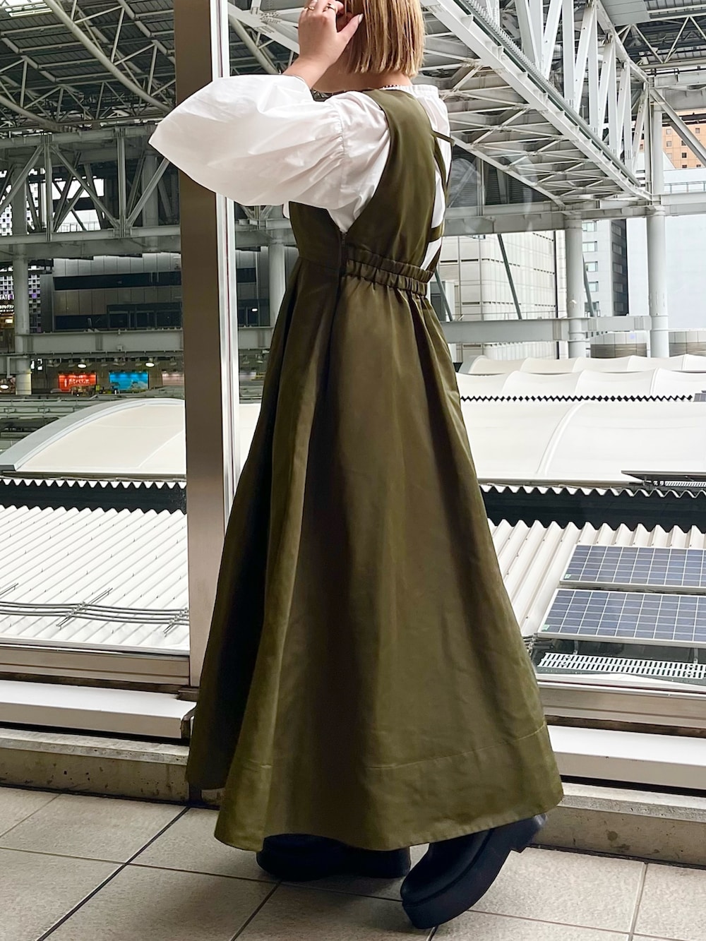 ホワイト系のシャツ/ブラウス、グリーン系のジャンパースカート、ブラック系のブーツを着用したレディースの春コーディネートの3枚目の写真