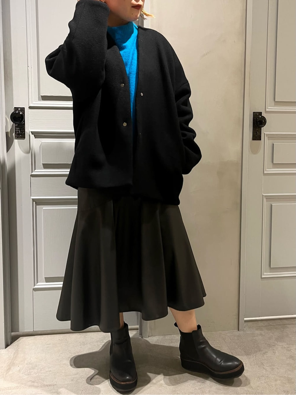 ブラック系のスカート、ブラック系のノーカラーコート、ブルー系のニット/セーターを着用したレディースの秋コーディネートの3枚目の写真