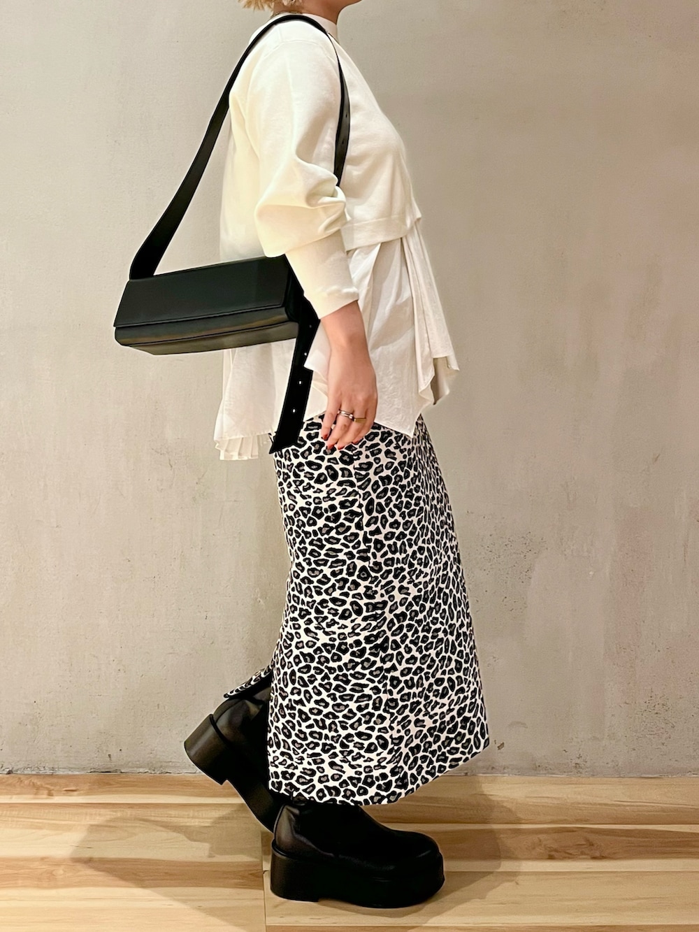 ホワイト系のスカート、ホワイト系のニット/セーター、ブラック系のショルダーバッグを着用したレディースの秋コーディネートの2枚目の写真