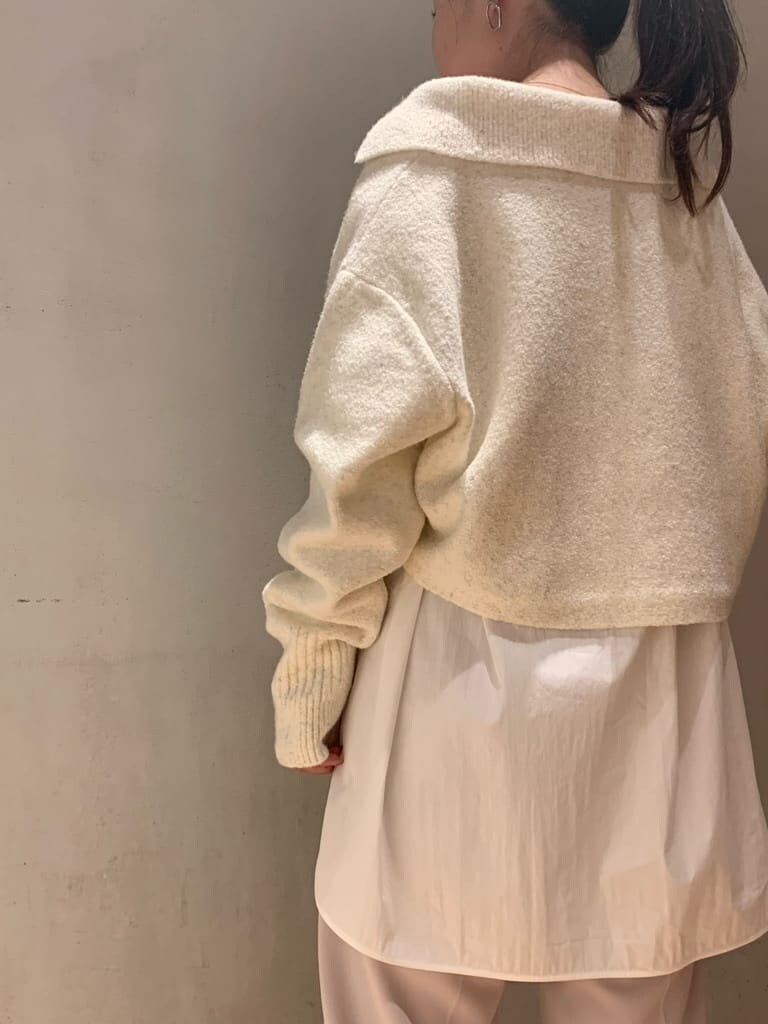 ブラウン系のスラックス、ブラック系のブーツ、ホワイト系のニット/セーターを着用したレディースの秋コーディネートの5枚目の写真