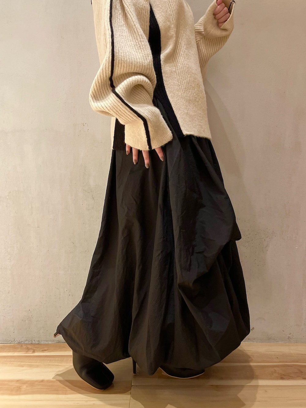 ブラック系のスカート、ホワイト系のニット/セーター、ブラック系のブーツを着用したレディースの秋コーディネートの9枚目の写真