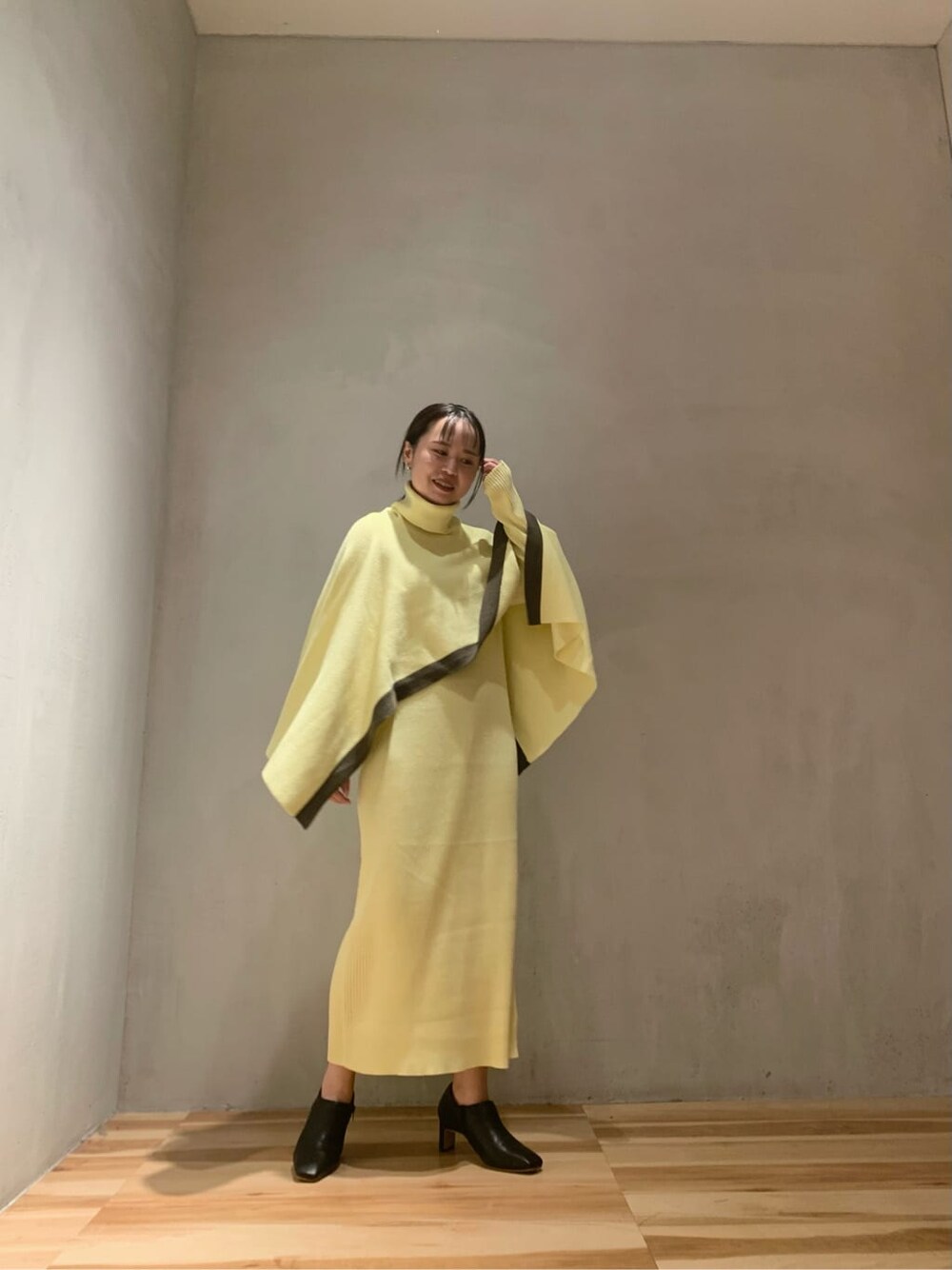 イエロー系のワンピース、ブラック系のブーツを着用したレディースの秋コーディネートの2枚目の写真