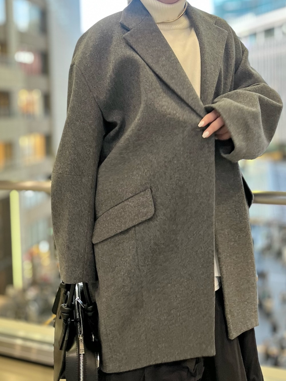 ブラック系のスカート、ブラック系のブーツ、ブラック系のハンドバッグを着用したレディースの冬コーディネートの5枚目の写真