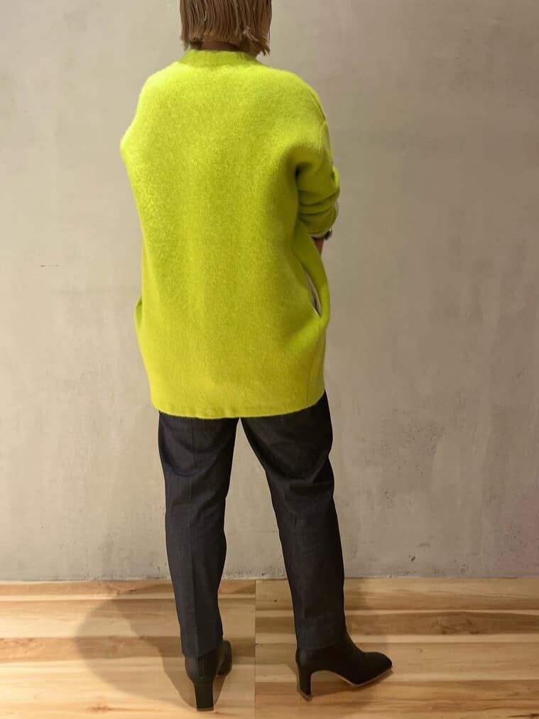 ホワイト系のショルダーバッグ、イエロー系のカーディガン/ボレロ、ブラック系のブーツを着用したレディースの秋コーディネートの3枚目の写真