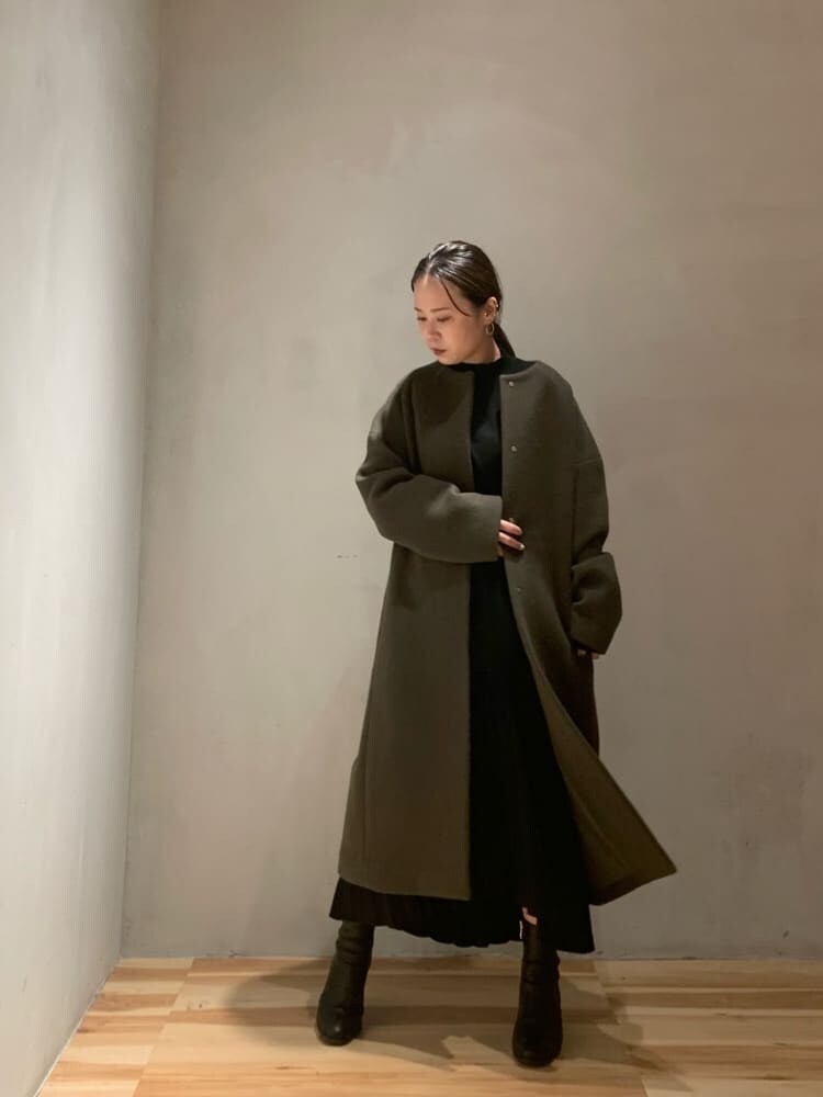 ブラック系のスカート、ブラック系のニット/セーター、ベージュ系のノーカラーコートを着用したレディースの秋コーディネートの2枚目の写真