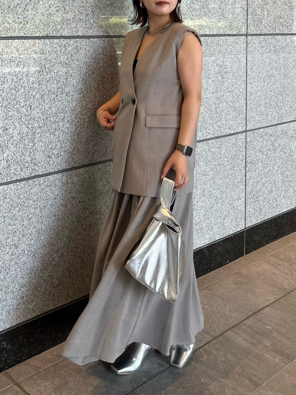 グレー系のワンピース、シルバー系のハンドバッグ、シルバー系のブーツを着用したレディースの夏コーディネートの3枚目の写真