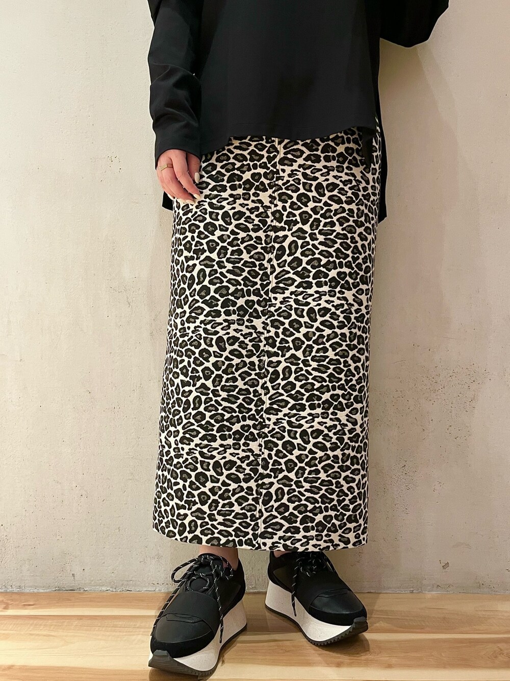 ブラック系のTシャツ/カットソー、ホワイト系のスカート、ブラック系のスニーカーを着用したレディースの春コーディネートの7枚目の写真