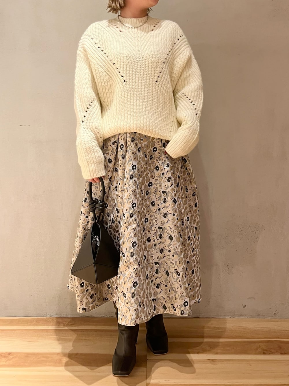 ベージュ系のスカート、ブラック系のハンドバッグ、ホワイト系のニット/セーターを着用したレディースの冬コーディネートの4枚目の写真
