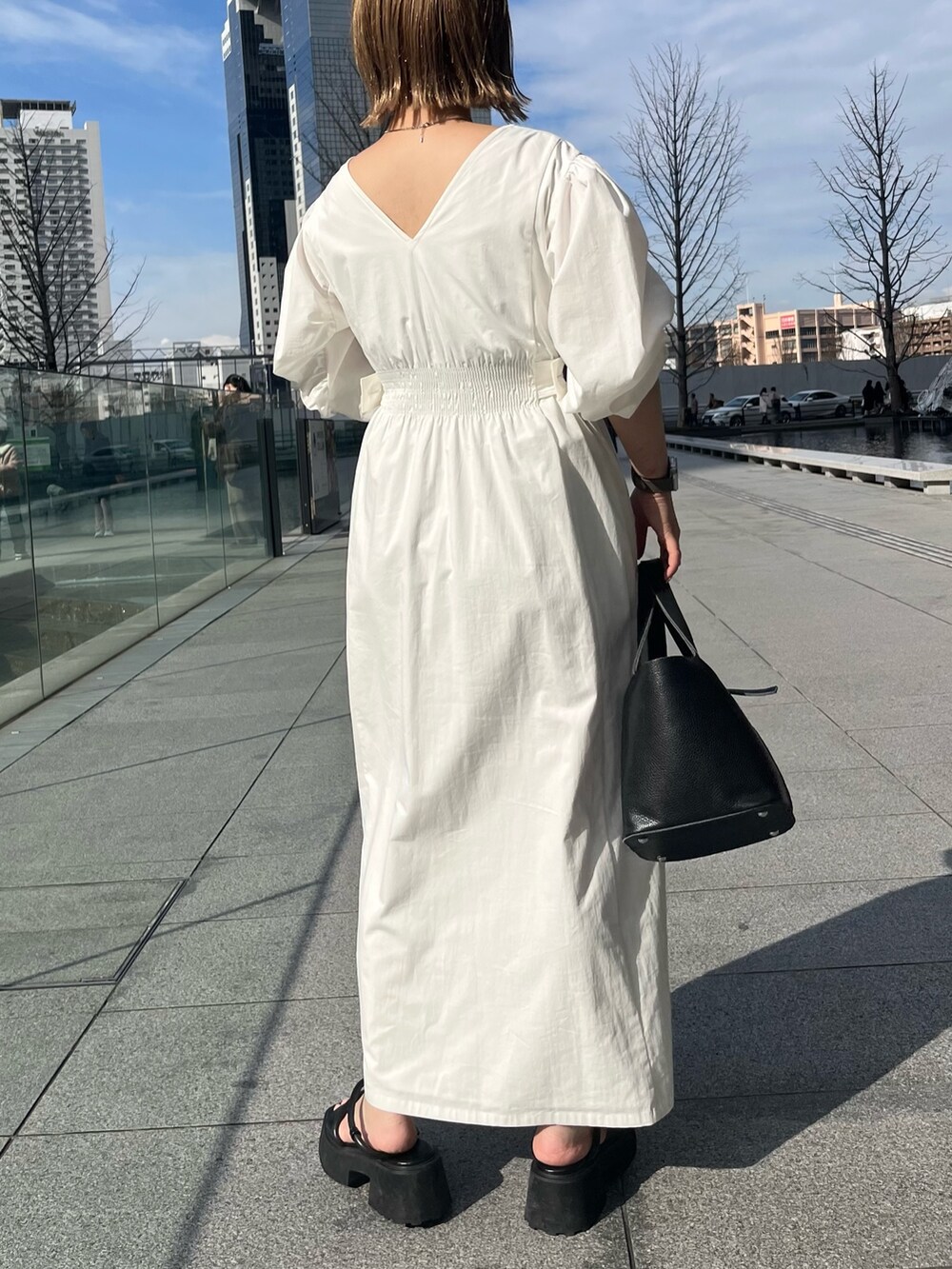 ブラック系のサンダル、ホワイト系のワンピース、ブラック系のハンドバッグを着用したレディースの冬コーディネートの3枚目の写真