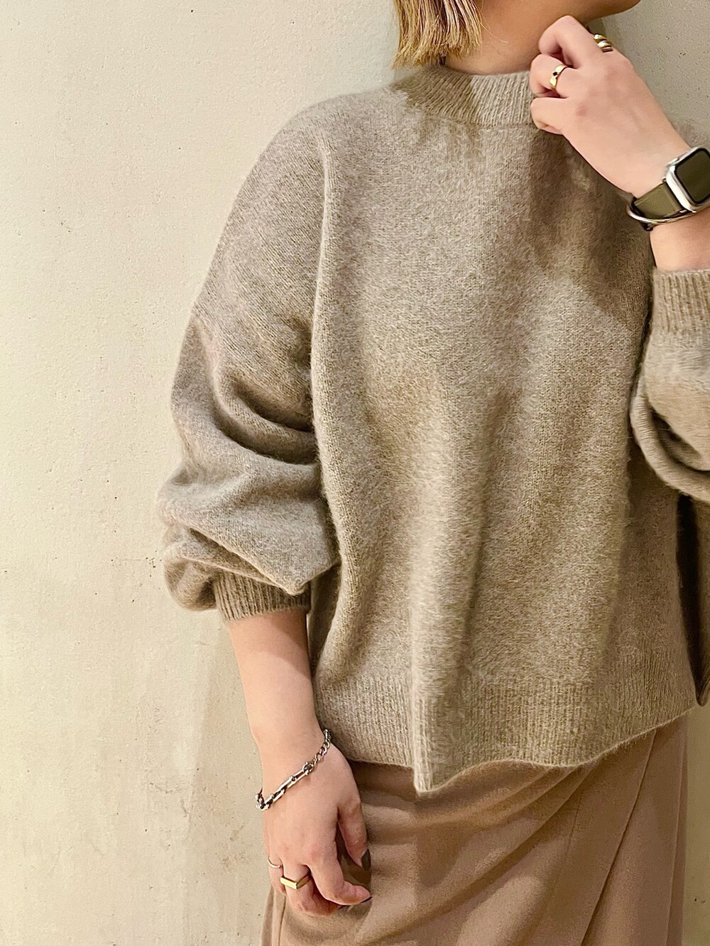 ベージュ系のニット/セーター、ベージュ系のスカート、ブラック系のブーツを着用したレディースの秋コーディネートの5枚目の写真