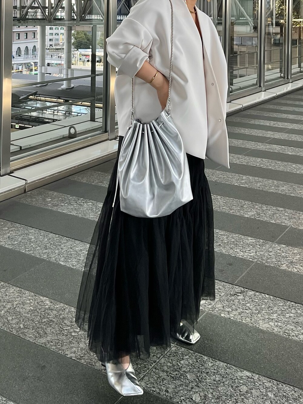 ベージュ系のノーカラーコート、ブラック系のタンクトップ、ブラック系のスカートを着用したレディースの冬コーディネートの2枚目の写真