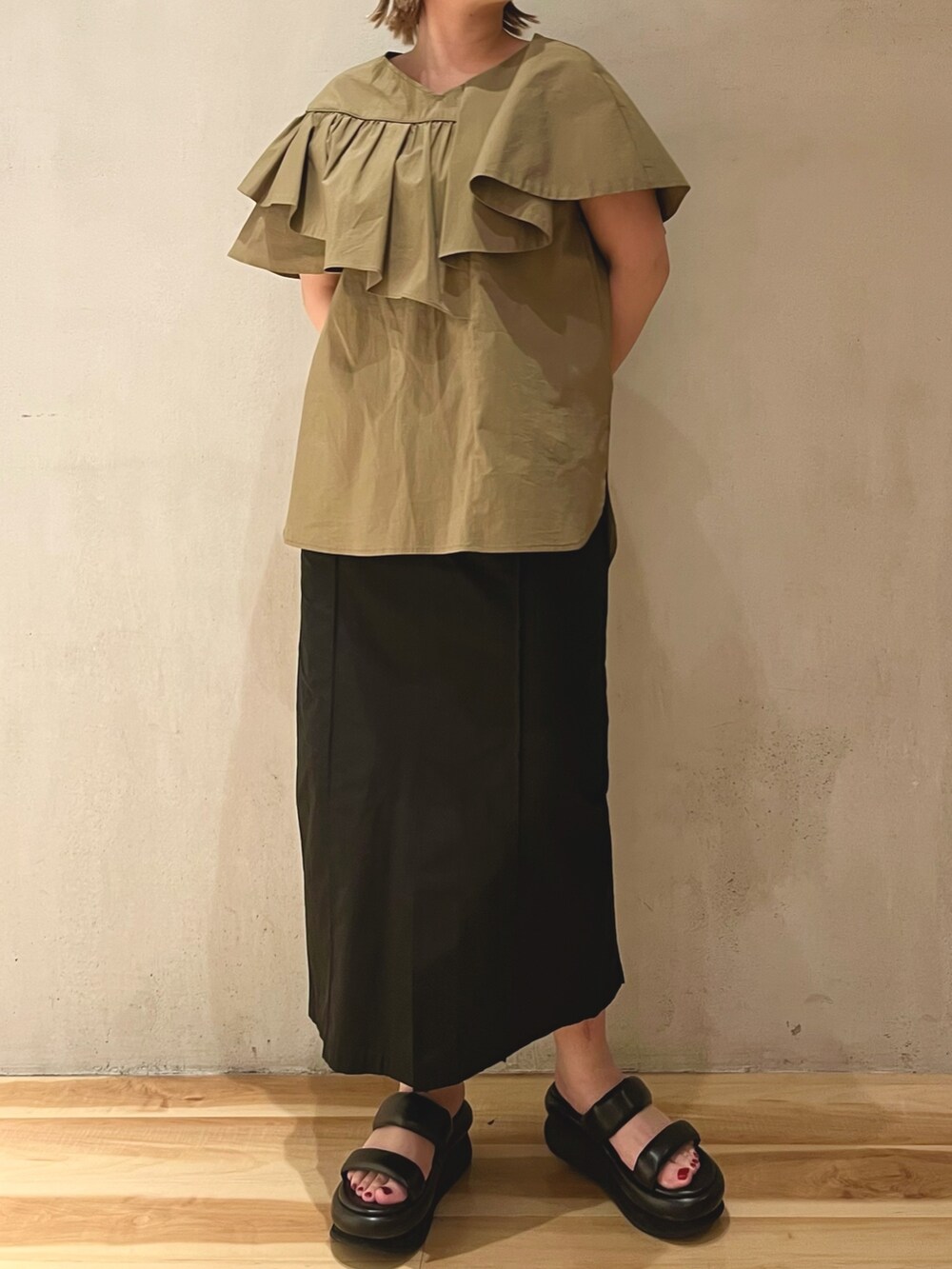 グリーン系のシャツ/ブラウス、ブラック系のスカート、ブラック系のサンダルを着用したレディースの冬コーディネートの4枚目の写真