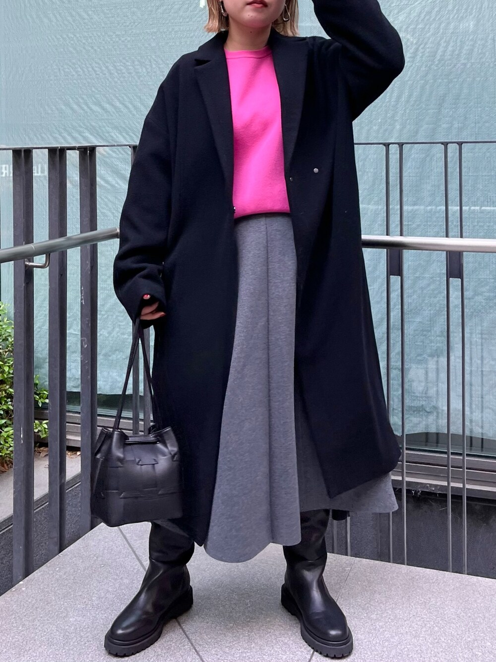 ピンク系のニット/セーター、ブラック系のチェスターコート、グレー系のスカートを着用したレディースの冬コーディネートの3枚目の写真