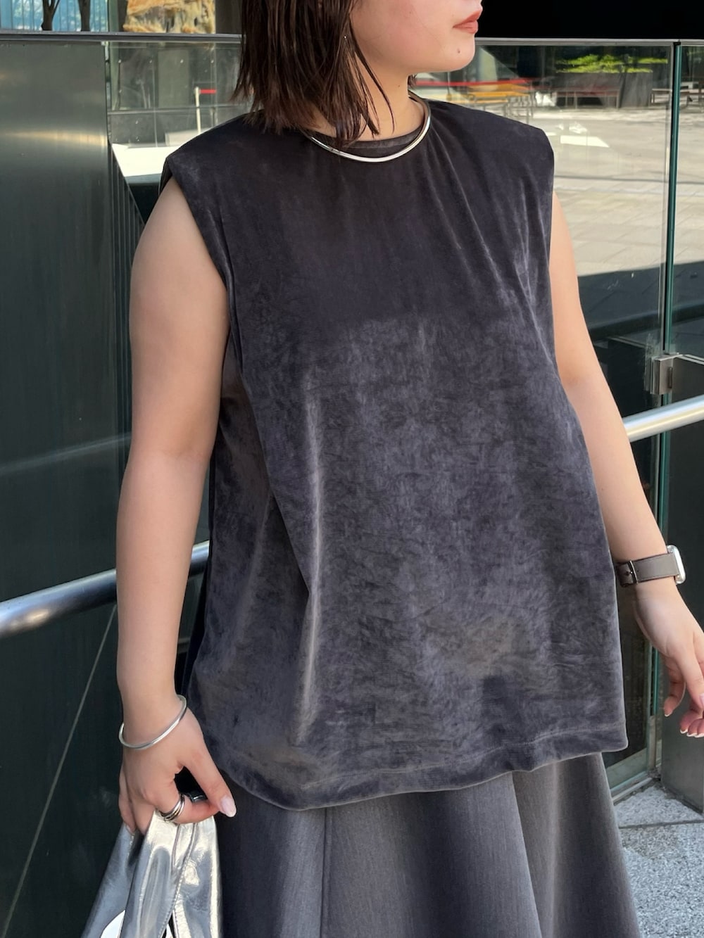 グレー系のスカート、ゴールド系のハンドバッグ、グレー系のTシャツ/カットソーを着用したレディースの夏コーディネートの7枚目の写真