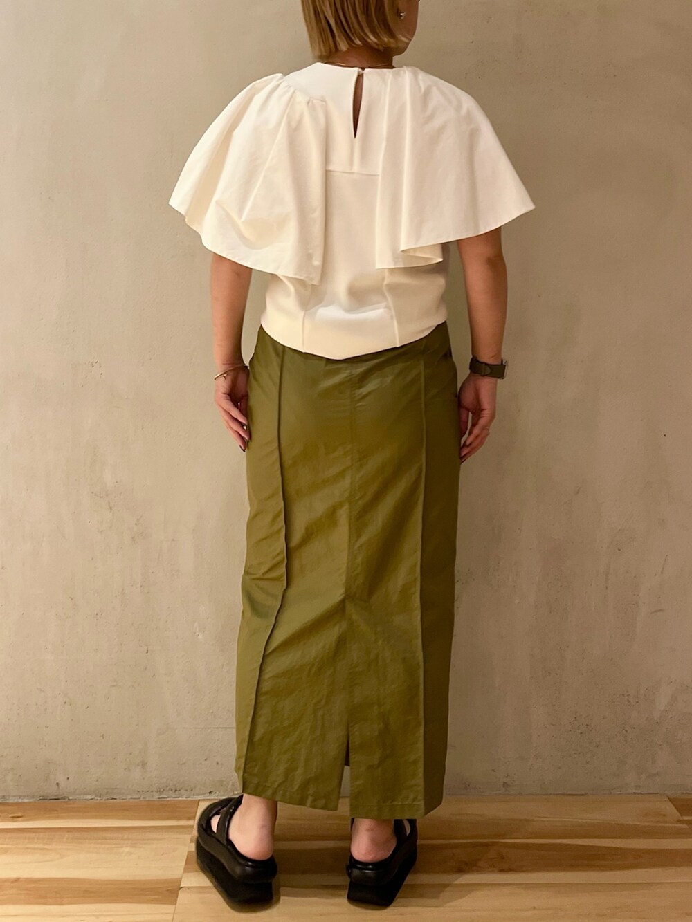 ホワイト系のTシャツ/カットソー、グリーン系のスカート、ブラック系のサンダルを着用したレディースの春コーディネートの3枚目の写真