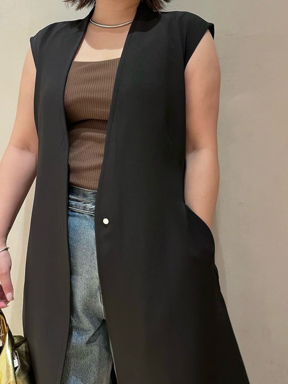 ブラック系のベスト、ブラウン系のタンクトップ、ブルー系のデニムパンツを着用したレディースの夏コーディネートの6枚目の写真