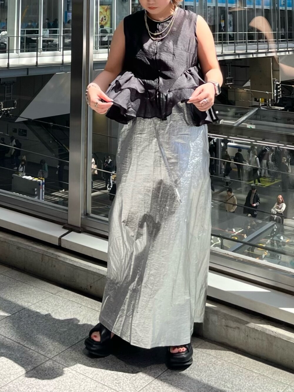 ブラック系のシャツ/ブラウス、シルバー系のスカート、ブラック系のサンダルを着用したレディースの春コーディネートの5枚目の写真