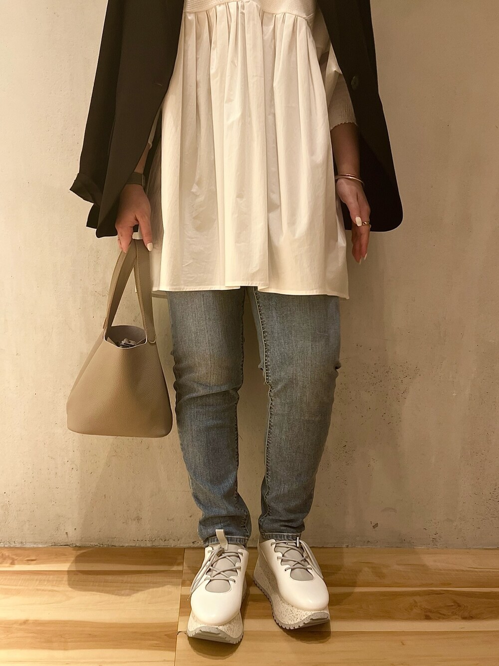 ブラック系のテーラードジャケット、ホワイト系のシャツ/ブラウス、ブルー系のデニムパンツを着用したレディースの冬コーディネートの8枚目の写真