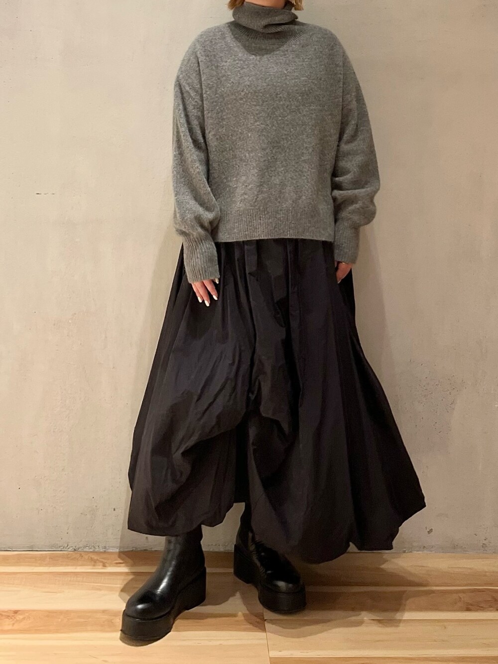 グレー系のニット/セーター、ブラック系のスカート、ブラック系のブーツを着用したレディースの冬コーディネートの5枚目の写真