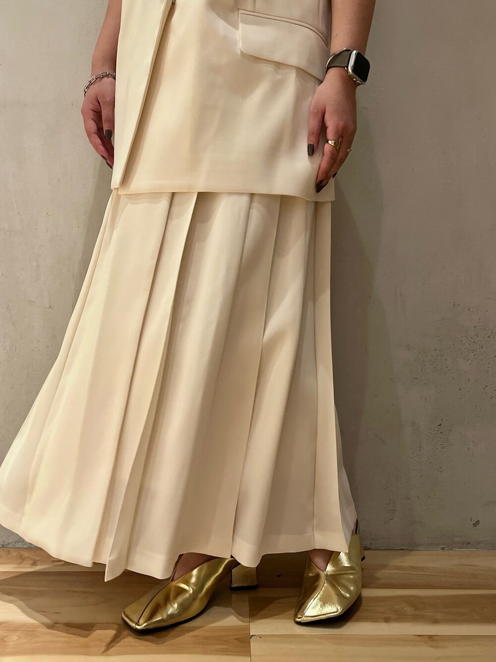 ゴールド系のパンプス、ホワイト系のスカート、ホワイト系のタンクトップを着用したレディースの冬コーディネートの9枚目の写真