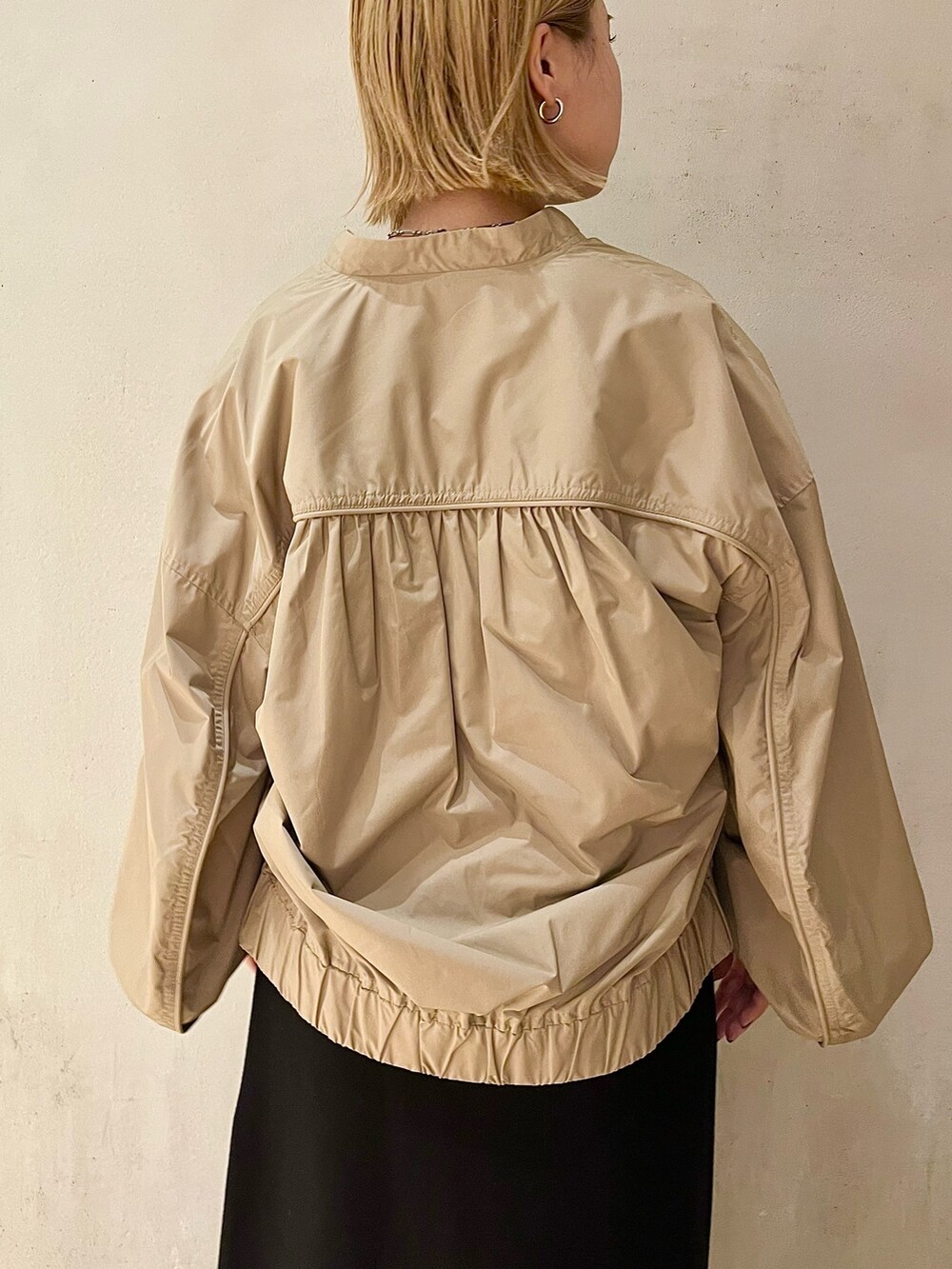 ベージュ系のブルゾン、ブラック系のスカート、ブラック系のブーツを着用したレディースの秋コーディネートの6枚目の写真