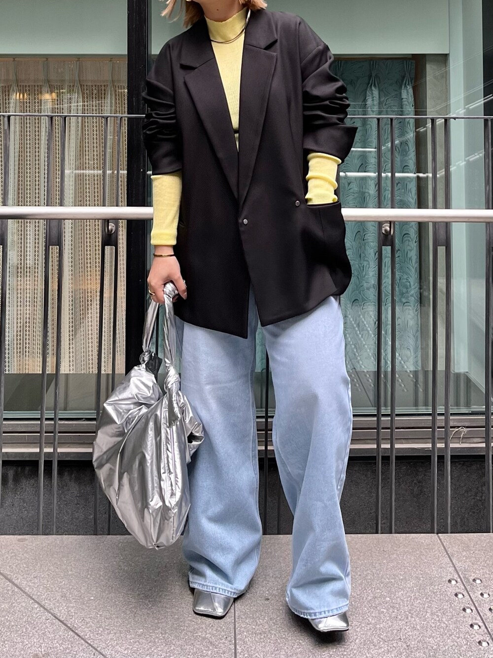 ブラック系のテーラードジャケット、イエロー系のニット/セーター、ブルー系のデニムパンツを着用したレディースの冬コーディネートの2枚目の写真