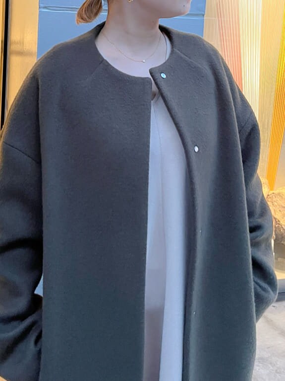 ホワイト系のショルダーバッグ、グリーン系のノーカラーコート、ベージュ系のワンピースを着用したレディースの秋コーディネートの4枚目の写真