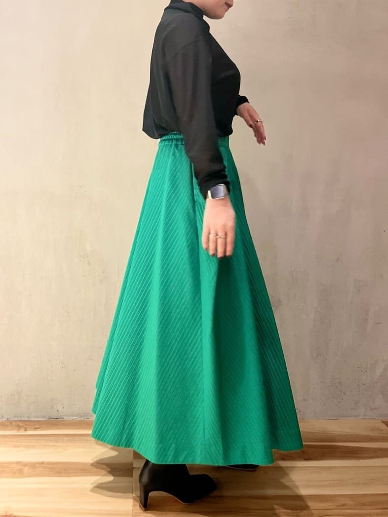 グリーン系のスカート、ブラック系のブーツ、ブラック系のTシャツ/カットソーを着用したレディースの夏コーディネートの2枚目の写真