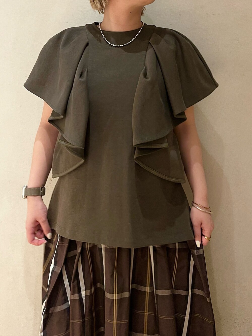 ブラック系のブーツ、グリーン系のTシャツ/カットソー、ブラウン系のスカートを着用したレディースの春コーディネートの4枚目の写真