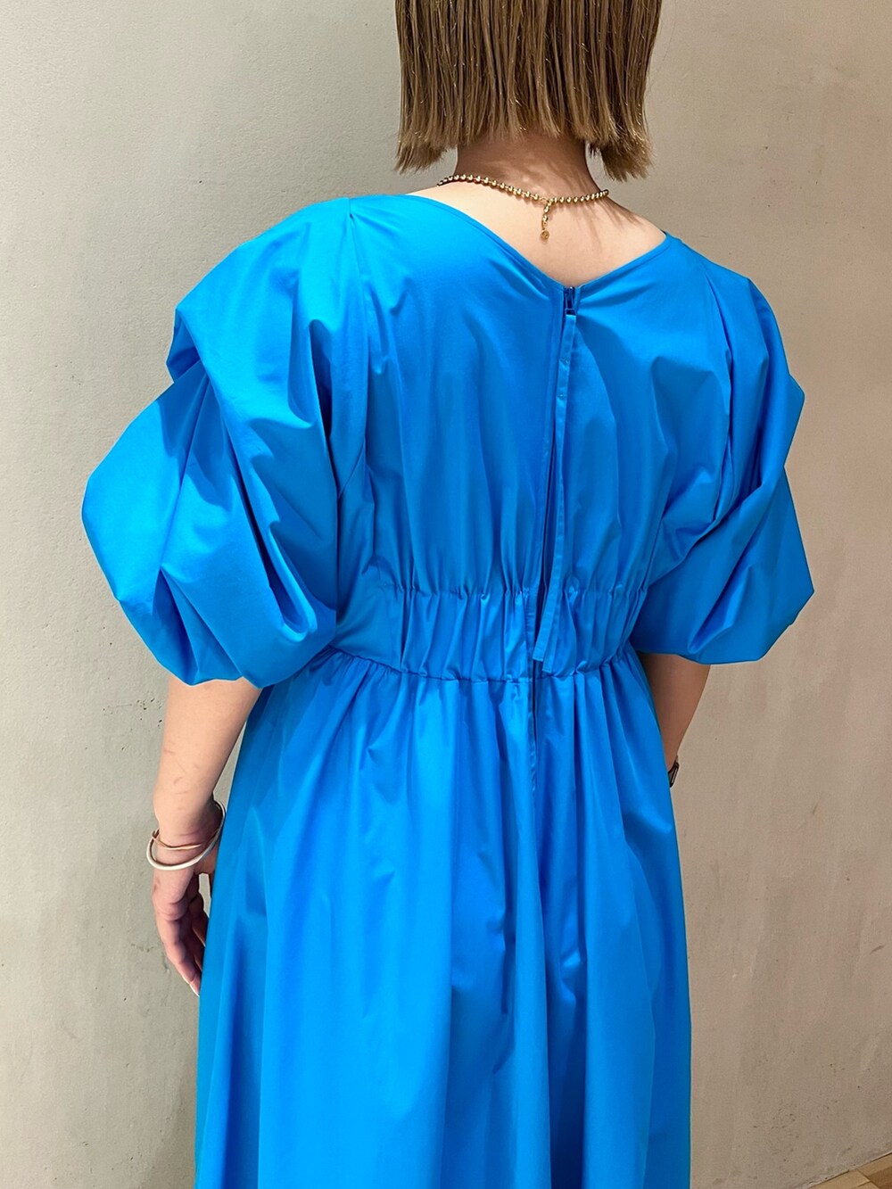 ブルー系のワンピース、ホワイト系のサンダル、ゴールド系のネックレスを着用したレディースの冬コーディネートの6枚目の写真