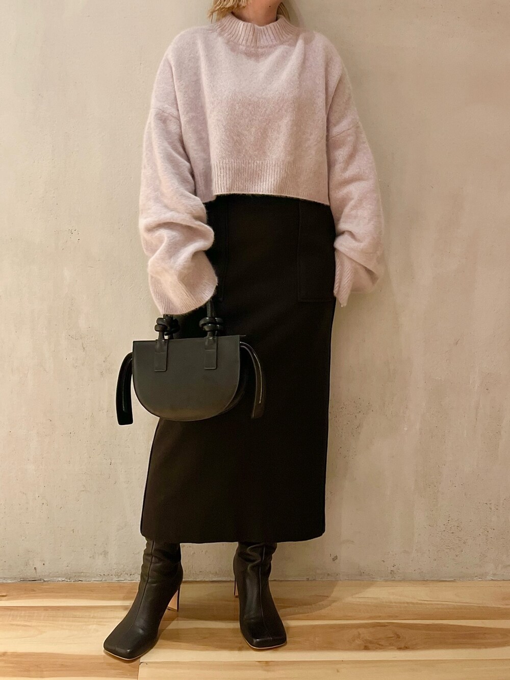 ブラック系のスカート、ブラック系のブーツ、ブラック系のハンドバッグを着用したレディースの秋コーディネートの2枚目の写真