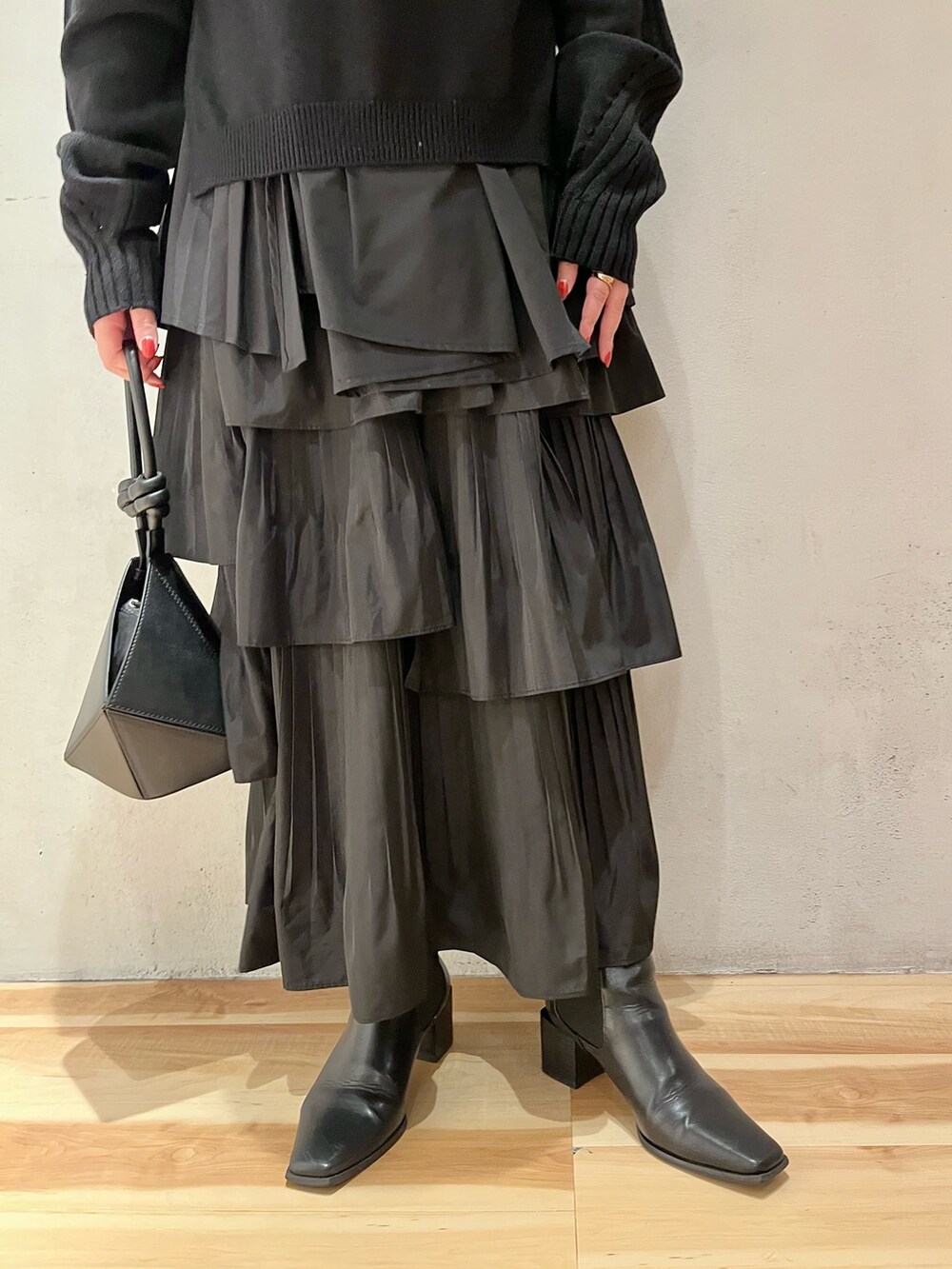 ブラック系のニット/セーター、ブラック系のハンドバッグ、ホワイト系のスカートを着用したレディースの秋コーディネートの9枚目の写真