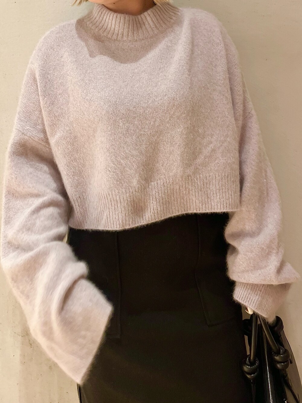 ブラック系のスカート、ブラック系のブーツ、ブラック系のハンドバッグを着用したレディースの秋コーディネートの4枚目の写真