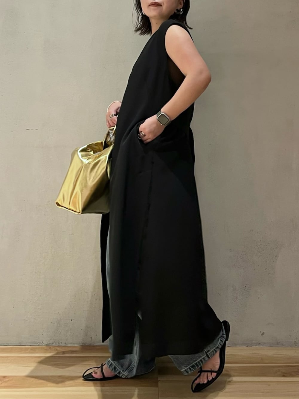 ブラック系のベスト、ブラウン系のタンクトップ、ブルー系のデニムパンツを着用したレディースの夏コーディネートの3枚目の写真