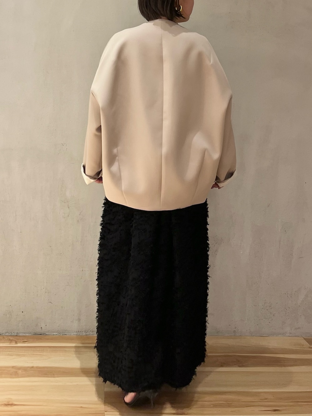 ブラック系のワンピース、ブラック系のタンクトップ、ベージュ系のノーカラーコートを着用したレディースの春コーディネートの3枚目の写真