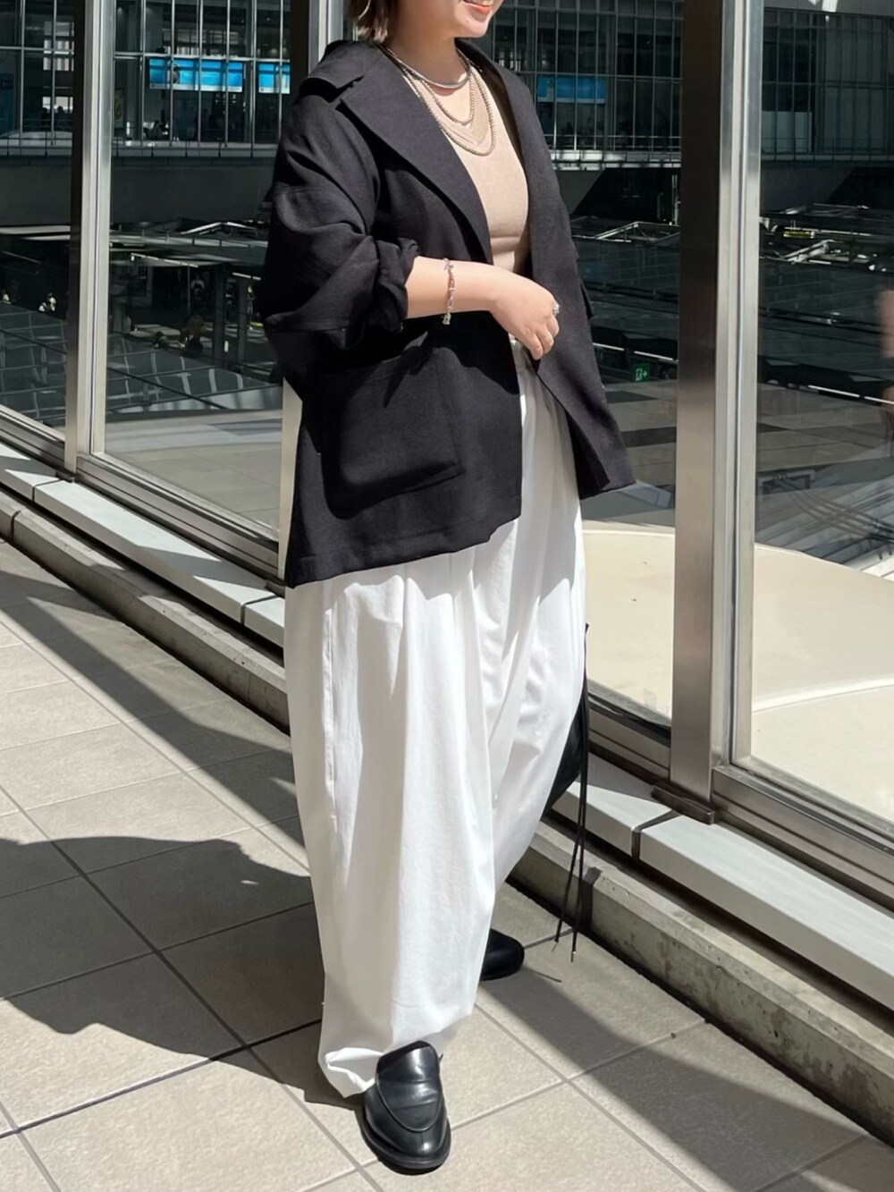 ブラック系のテーラードジャケット、ベージュ系のニット/セーター、ホワイト系のその他パンツを着用したレディースの春コーディネートの2枚目の写真