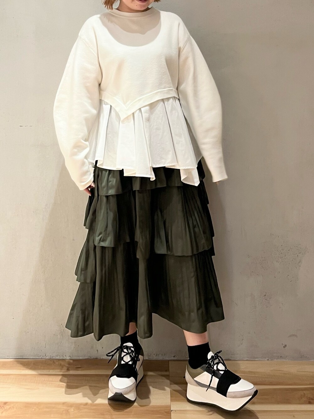 ホワイト系のニット/セーター、ベージュ系のスカート、ブルー系のスニーカーを着用したレディースの秋コーディネートの2枚目の写真