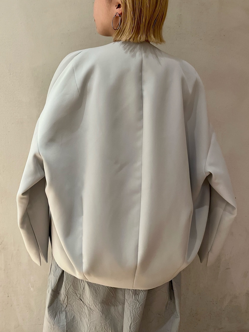 ブルー系のノーカラーコート、シルバー系のパンプス、ブルー系のワンピースを着用したレディースの冬コーディネートの6枚目の写真