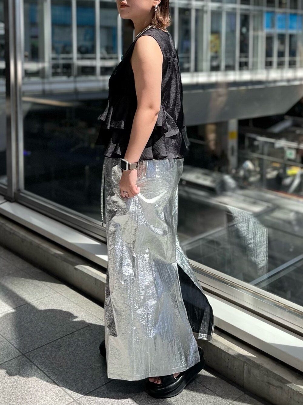 ブラック系のシャツ/ブラウス、シルバー系のスカート、ブラック系のサンダルを着用したレディースの春コーディネートの2枚目の写真