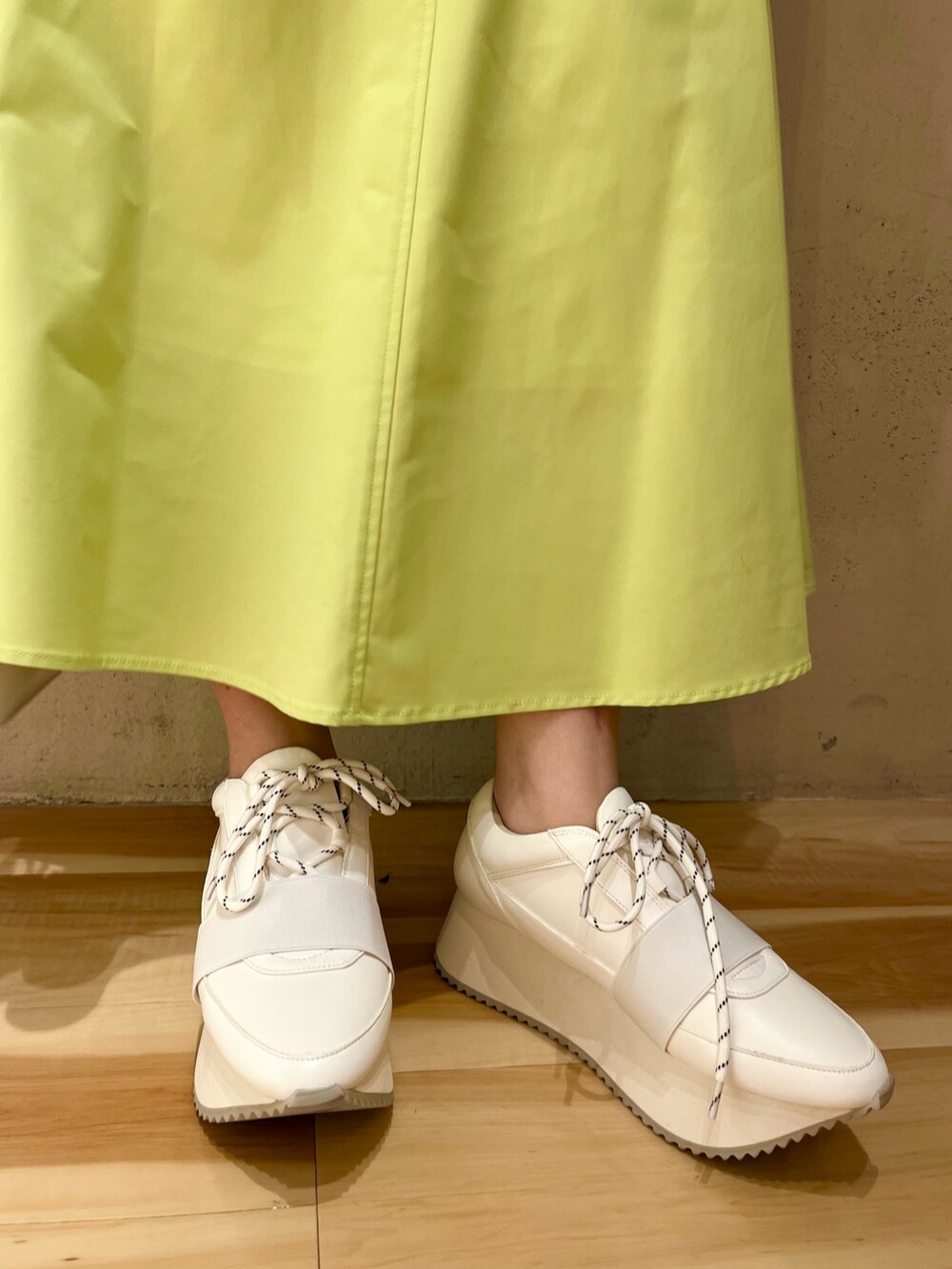 ベージュ系のノーカラーコート、グリーン系のニット/セーター、ベージュ系のショルダーバッグを着用したレディースの冬コーディネートの8枚目の写真