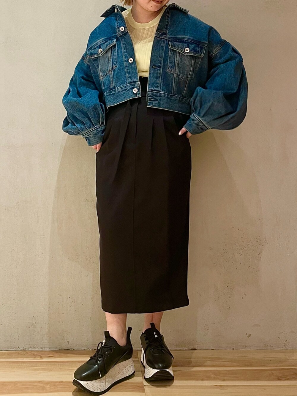 ブルー系のデニムジャケット、イエロー系のニット/セーター、ブラック系のスカートを着用したレディースの冬コーディネートの4枚目の写真