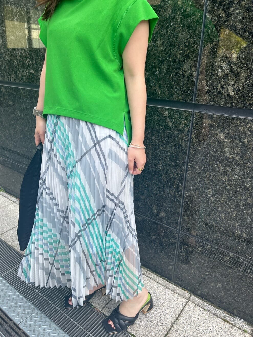 ブラック系のサンダル、グリーン系のTシャツ/カットソー、ホワイト系のスカートを着用したレディースの春コーディネートの4枚目の写真