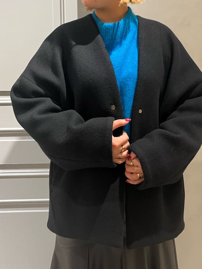 ブラック系のスカート、ブラック系のノーカラーコート、ブルー系のニット/セーターを着用したレディースの秋コーディネートの5枚目の写真