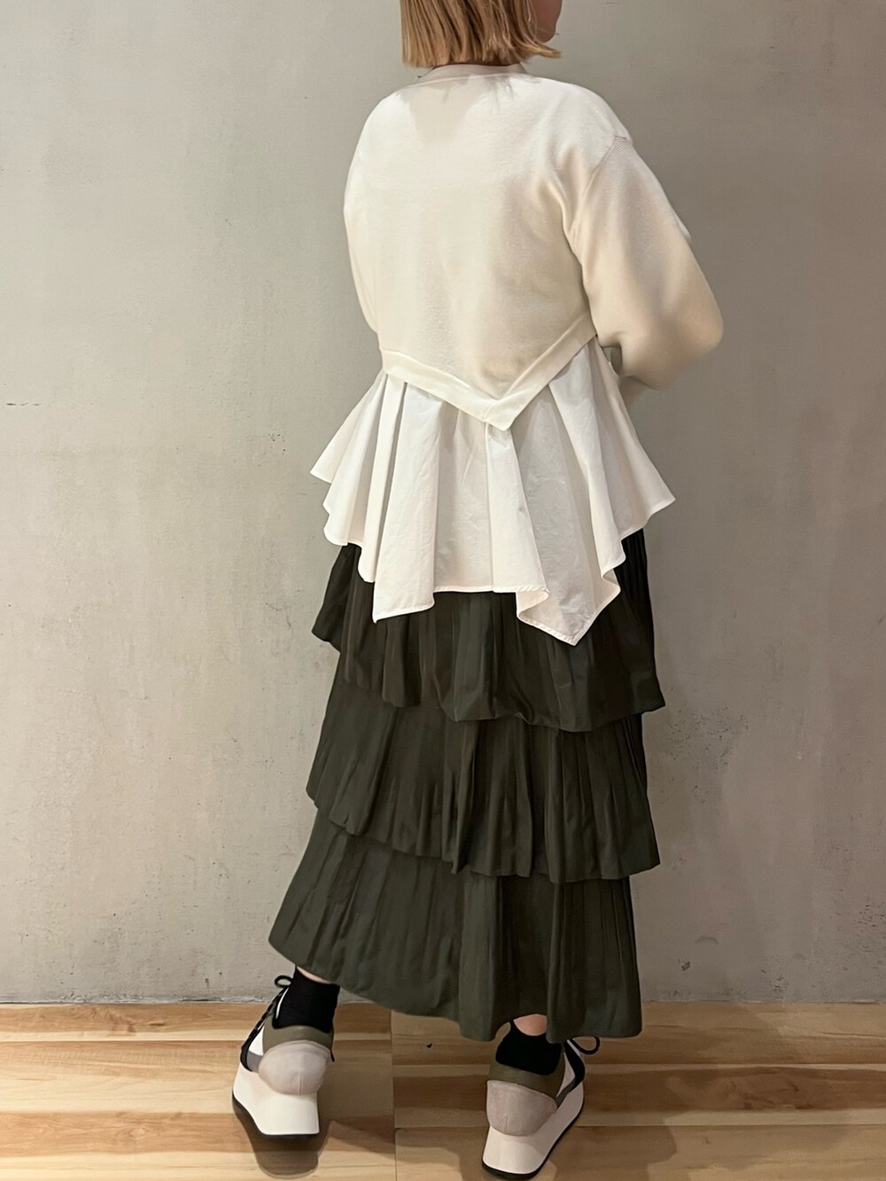 ホワイト系のニット/セーター、ベージュ系のスカート、ブルー系のスニーカーを着用したレディースの秋コーディネートの4枚目の写真