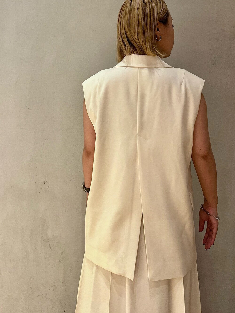 ゴールド系のパンプス、ホワイト系のスカート、ホワイト系のタンクトップを着用したレディースの冬コーディネートの6枚目の写真